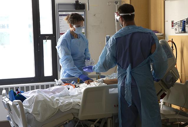 Nurses Karen Hayes, left, and Nurse Nick Brideau care for a patient in COVID-19 unit at Harborview Medical Center in mid-2020. Getty Images.