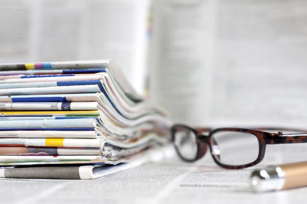 Stack of journals next to a pen and glasses