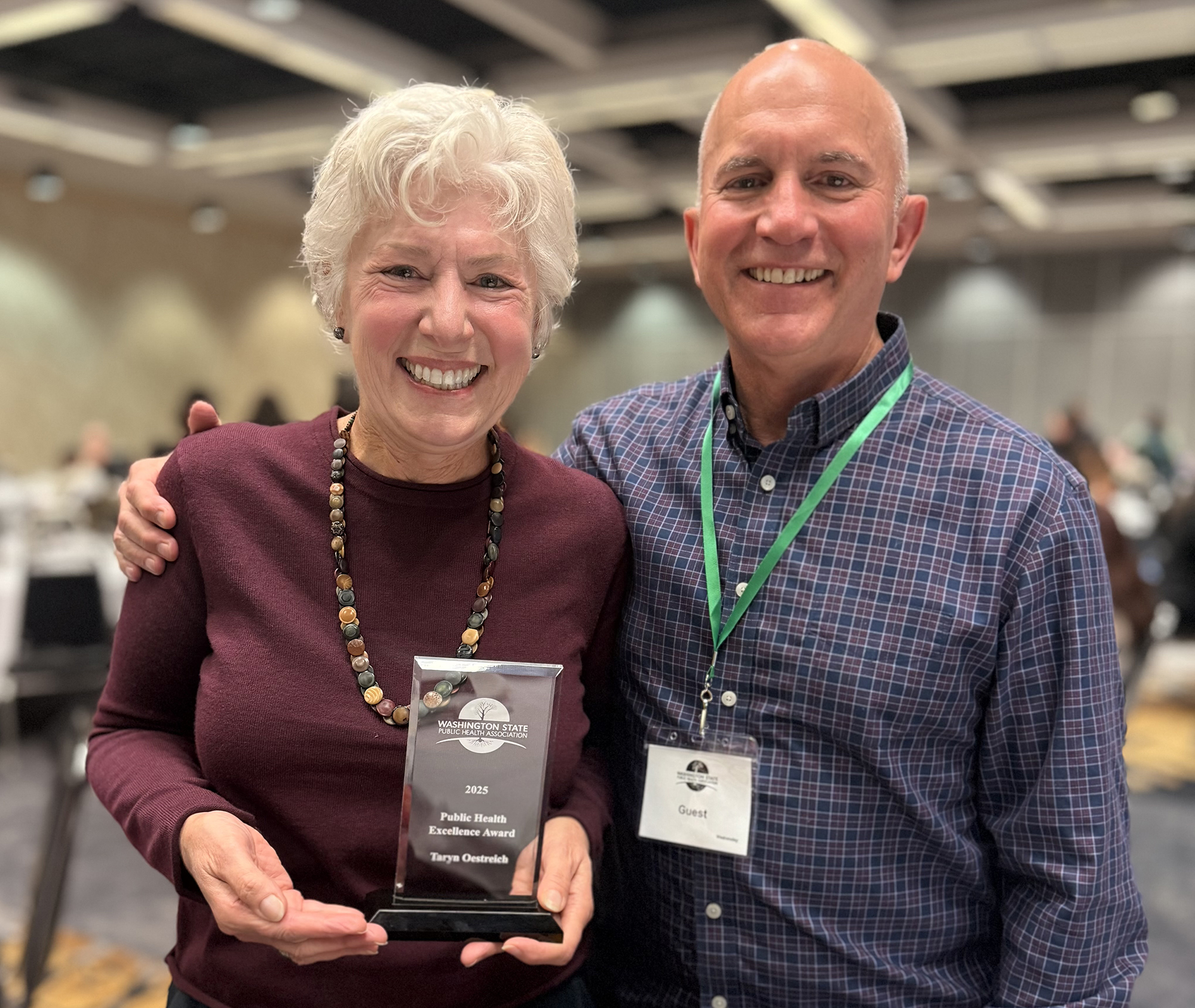 Taryn Oestreich and her husband. Taryn is holding an award. 