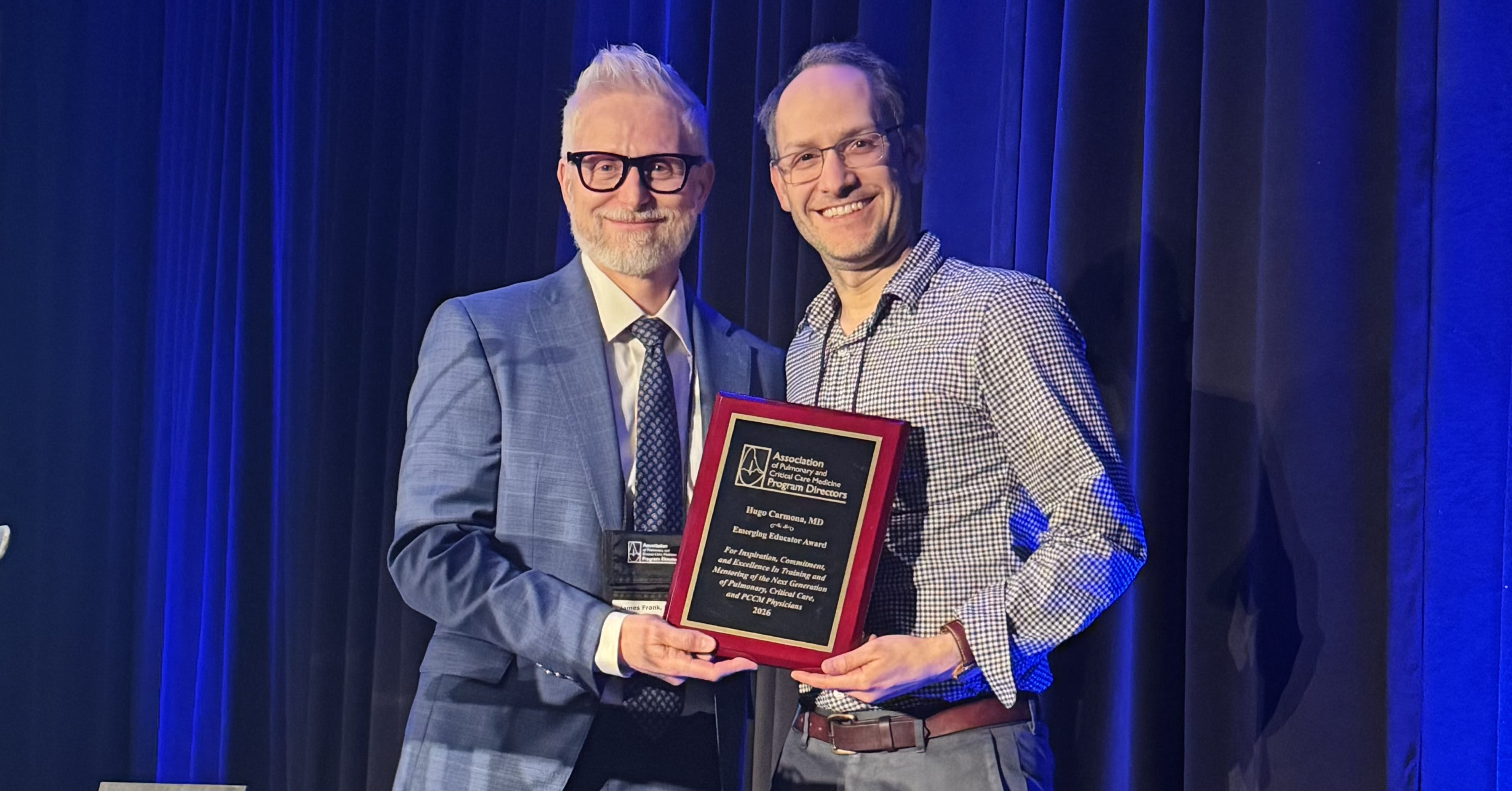 Hugo Carmona receiving Emerging Educator Award/holding up the plaque and smiling. 