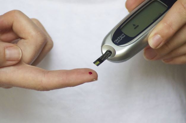 finger with blood drop and glucometer