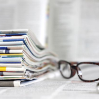 Stack of journals next to a pen and glasses