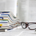 Stack of journals next to a pen and glasses