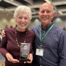 Taryn Oestreich and her husband. Taryn is holding an award. 